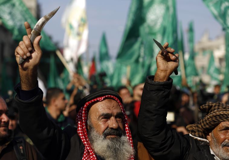 Palestinians carry knives and daggers as they attend a military parade of members of al-Qassam Brigades, the armed wing of the Hamas movement, to mark the 28th anniversary. (photo credit:MOHAMMED ABED / AFP)
