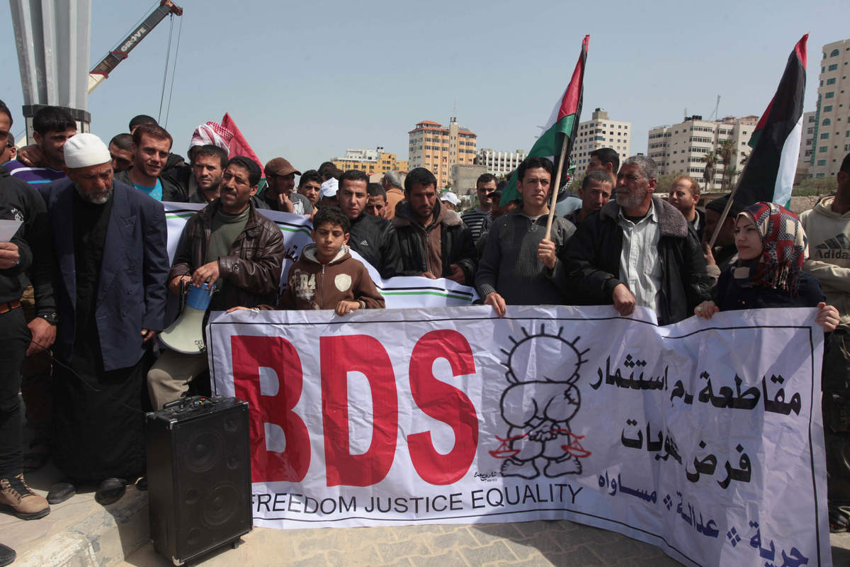 Palestinian fishermen hold banners in a protest to demand the boycott of the Israeli agricultural products, during the 10th annual Israeli Apartheid Week, at the seaport of Gaza City on March 16, 2014. (Photo: Ashraf Amra/APA Images)