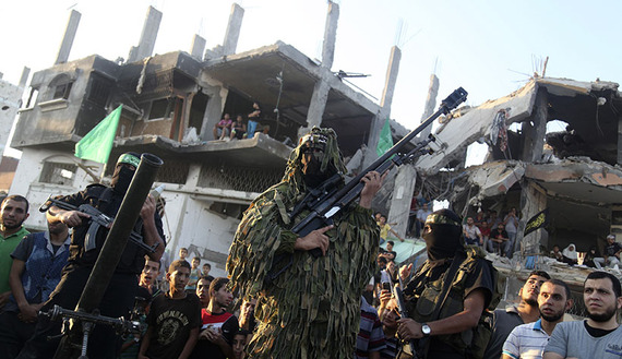 Hamas militants display weapons in front of a destroyed house east of Gaza City, Aug. 27, 2014. (photo by REUTERS/Majdi Fathi)