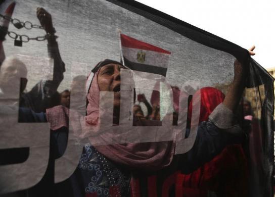 A protester who opposes Egyptian President Mohamed Mursi, is seen through a flag, on which the word Egyptian is inscribed, as she chants slogans during a demonstration against Mursi and members of the Muslim Brotherhood at Tahrir Square in Cairo,