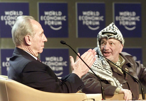 Shimon Peres, Minister of Regional Cooperation of Israel, left, applauds Palestinian leader Yasser Arafat, right, as it is announced that Arafat is about to speak at the Davos World Economic Forum. Both took part in the forum on "From Peacemaking to Peacebuilding." Peres, a former Israeli president and prime minister, whose life story mirrored that of the Jewish state and who was celebrated around the world as a Nobel prize-winning visionary who pushed his country toward peace. (AP Photo/Herbert Knosowski)